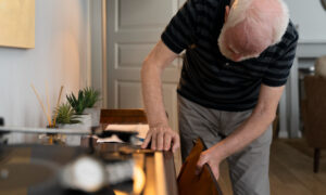 седой старик заглядывает в комод