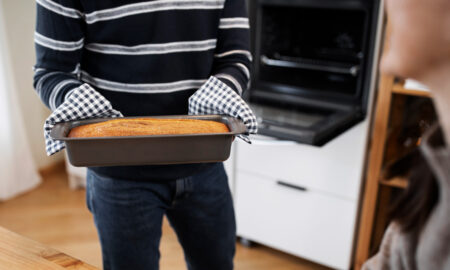 Мужчина держит в руках форму для выпечки с пирогом внутри