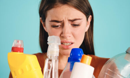 девушка с озадаченным видом смотрит на банки из-под бытовой химии