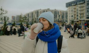 Женщина в пальто пьет кофе