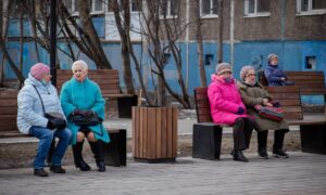 Пенсионеры сидят на скамейках в парке
