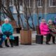 Пенсионеры сидят на скамейках в парке