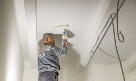 рабочий красит потолок