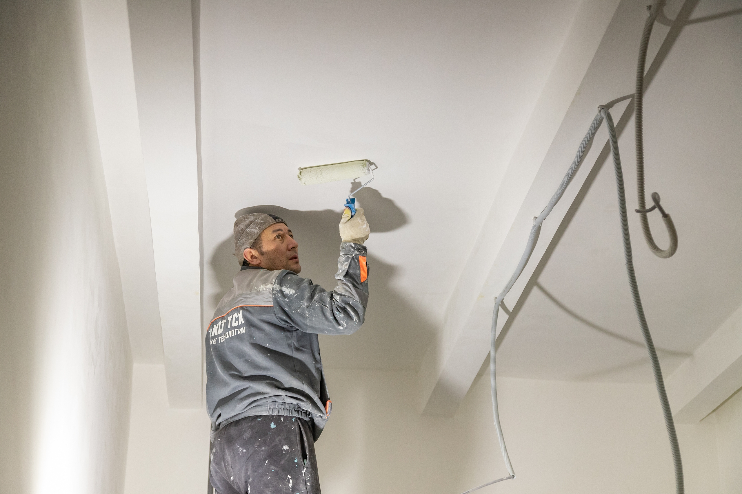 рабочий красит потолок