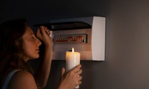 девушка со свечой проверяет электрический щиток