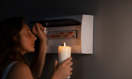 девушка со свечой проверяет электрический щиток