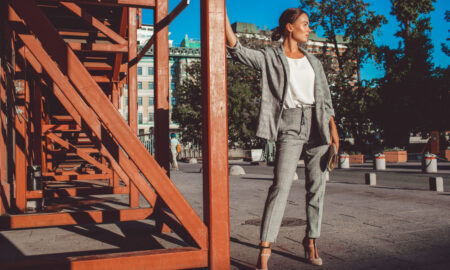 Девушка в брючном костюме гуляет по городу.