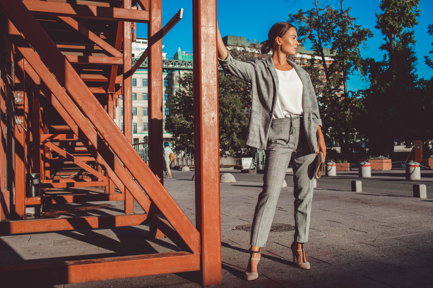 Девушка в брючном костюме гуляет по городу.