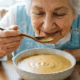Бабушка кушает овощной суп-пюре.