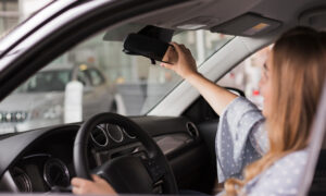 Женщина поправляет зеркало заднего вида