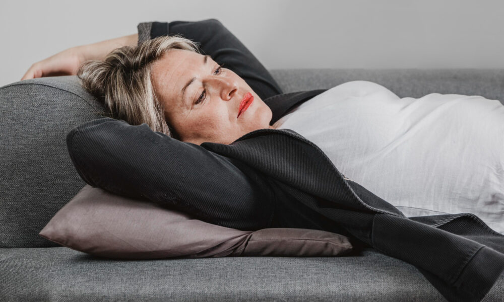 Уставшая женщина спит на диване