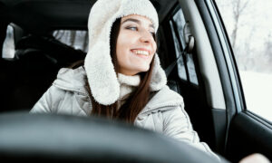 Улыбающаяся женщина позирует в машине за рулём