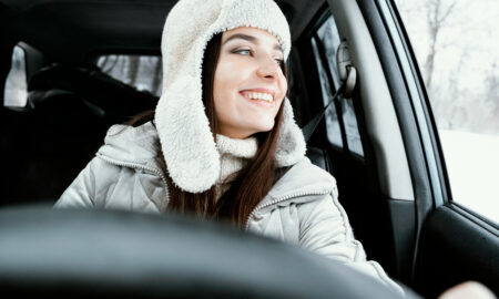 Улыбающаяся женщина позирует в машине за рулём