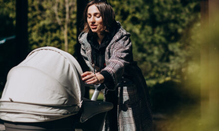 Молодая мать гуляет с детской коляской в ​​парке