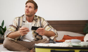 Мужчина держит в руках телефон и кредитку