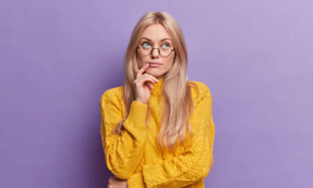 Девушка в очках и желтом свитере думает