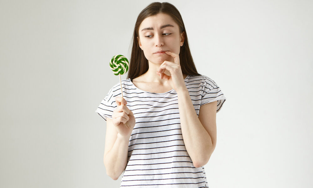 Девушка в полосатой футболке с леденцом на палочке