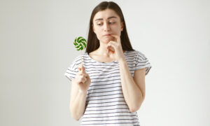 Девушка в полосатой футболке с леденцом на палочке