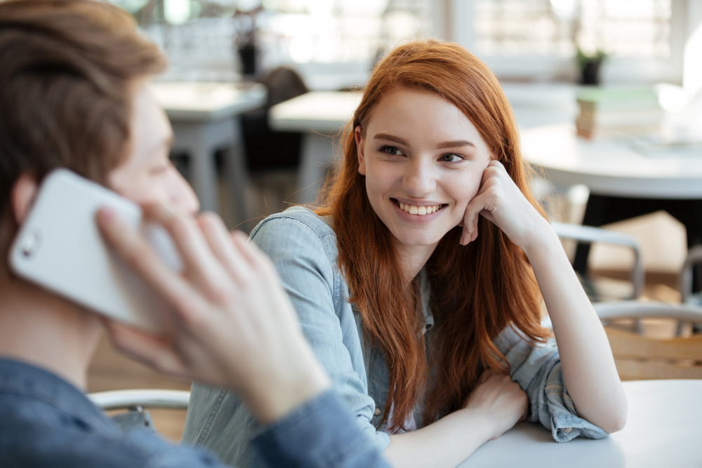 Рыжеволосая девушка и парень в кафе