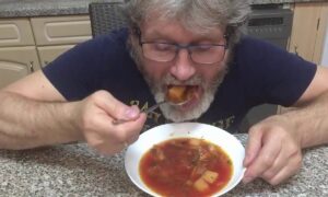 Мужчина ест борщ
