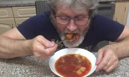 Мужчина ест борщ