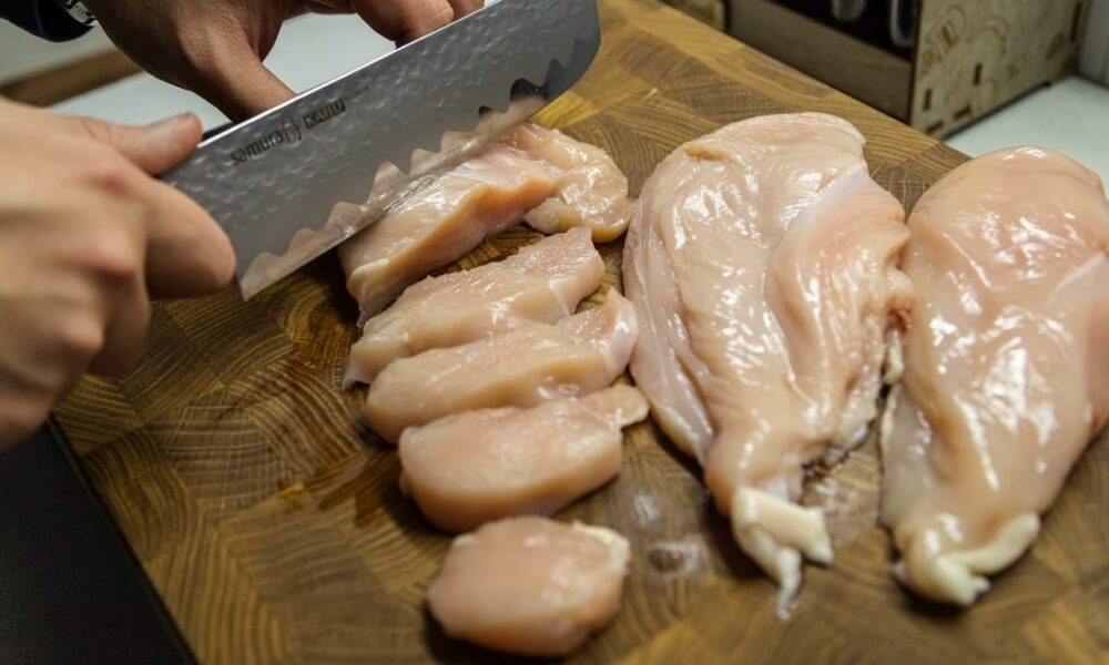 Повар режет куриную грудку