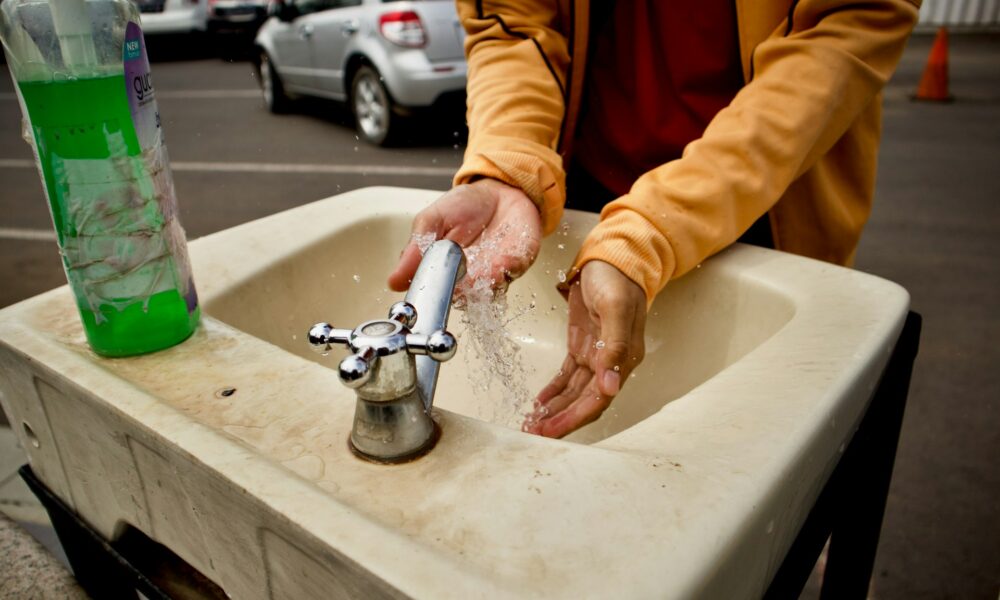 Моет руки в раковине