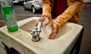 Моет руки в раковине