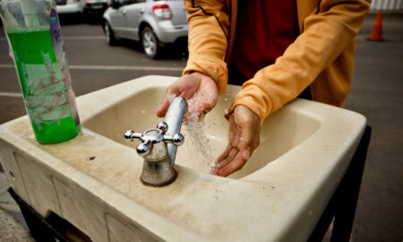 Моет руки в раковине