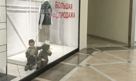 Дети за стеклом с надписью Распродажа