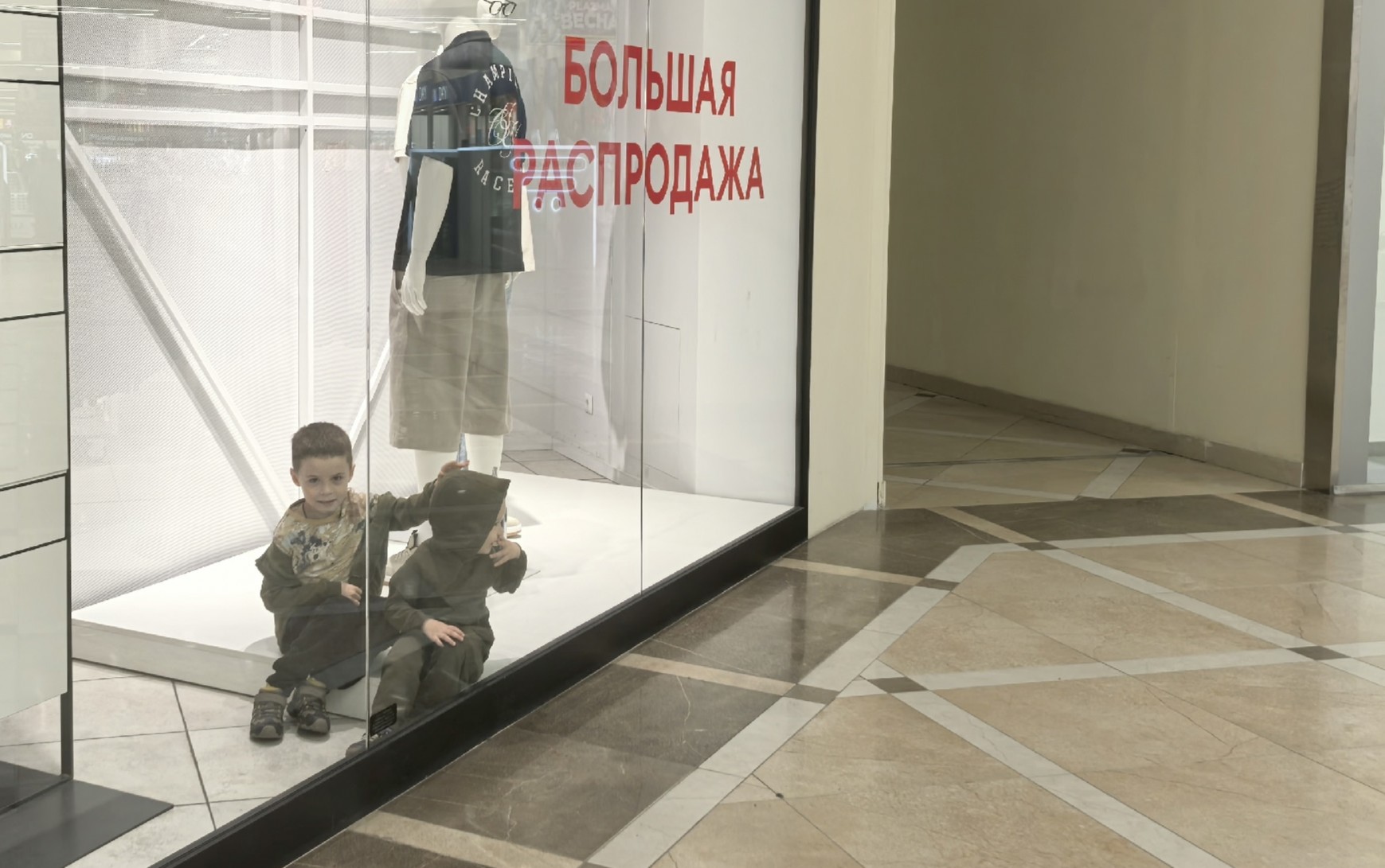 Дети за стеклом с надписью Распродажа