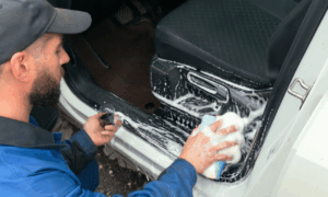 Водитель моет автомобиль