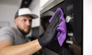 Мужчина протирает тряпкой микроволновку