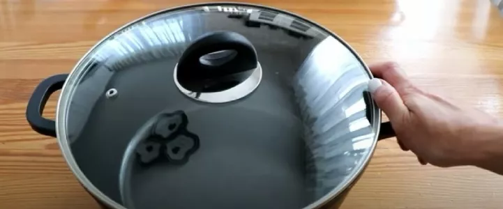 Человек держит рукой кастрюлю