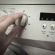Человек переключает режим на стиральной машине