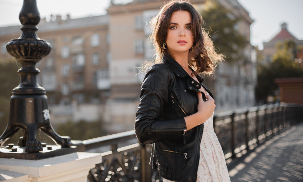 Девушка в кожаной куртке позирует у воды