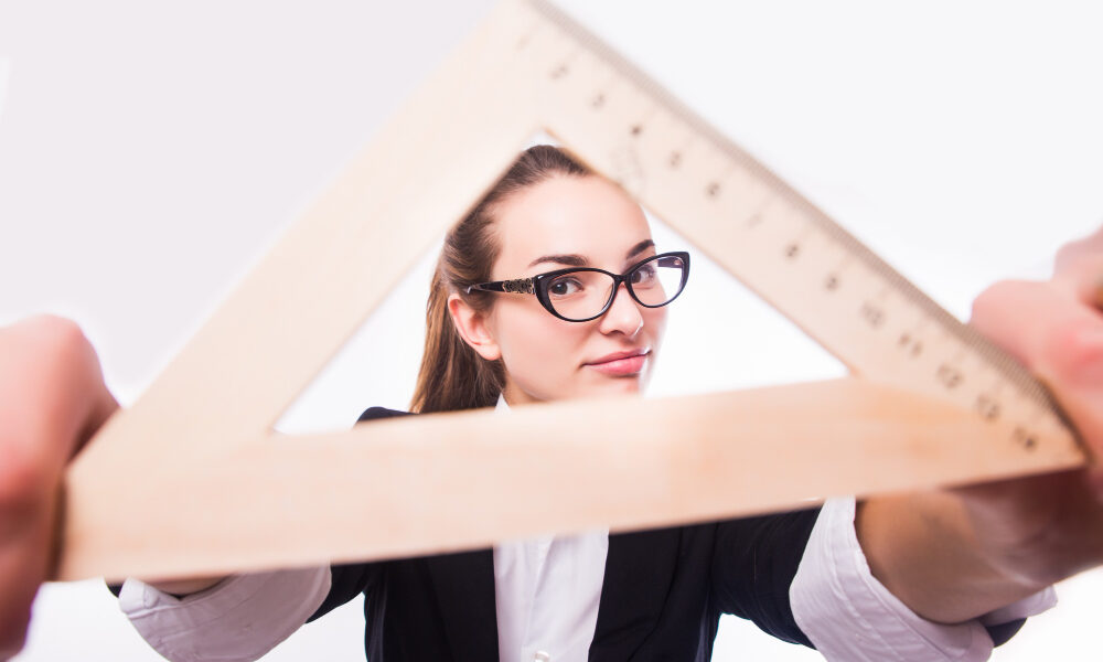 Девушка держит перед собой деревянную линейку - треугольник.