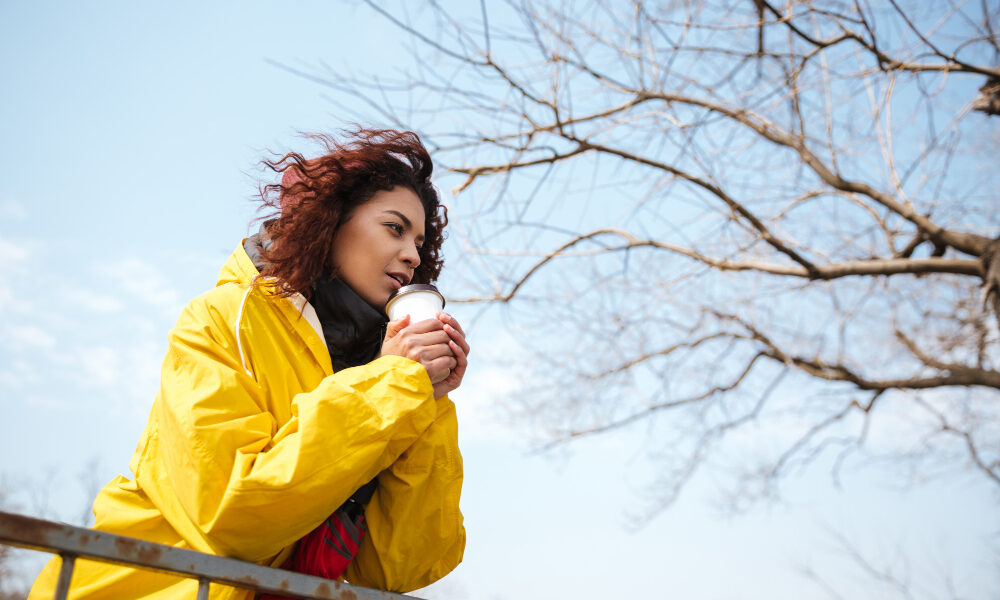 Девушка в жёлтой куртке на фоне голубого неба.