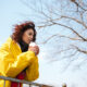 Девушка в жёлтой куртке на фоне голубого неба.