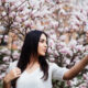 Девушка делает селфи на фоне цветущих весной веток.