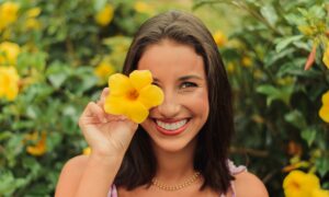 Женщина с цветком улыбается