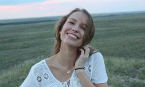 Девушка улыбается на фоне поля