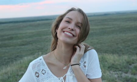 Девушка улыбается на фоне поля