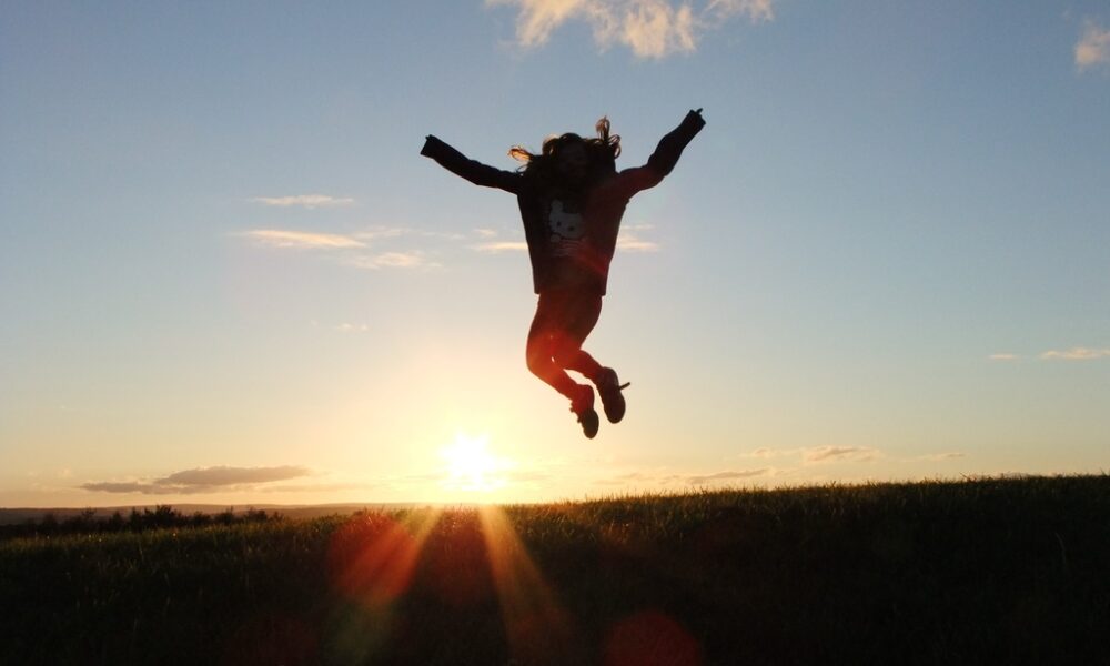 Девушка подпрыгивает с поднятыми руками