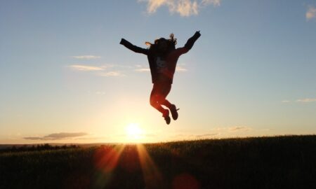 Девушка подпрыгивает с поднятыми руками