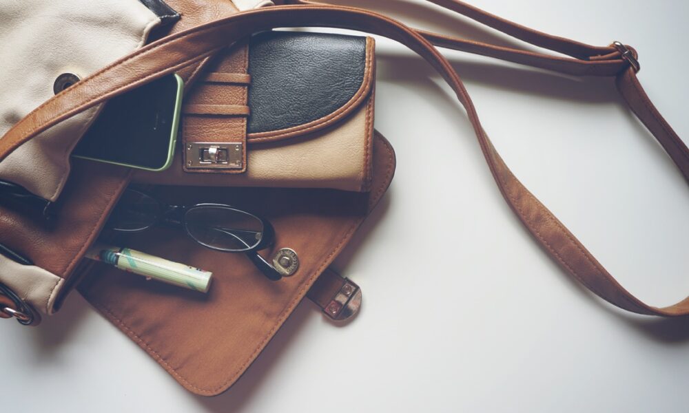 Женская сумка и очки лежат на столе