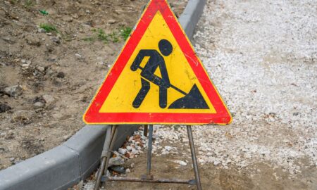 Желтый дорожный знак Ремонтные работы на фоне земли