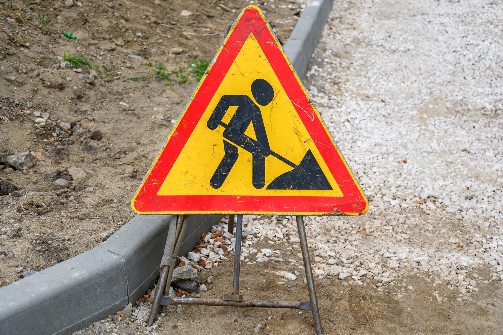 Желтый дорожный знак Ремонтные работы на фоне земли