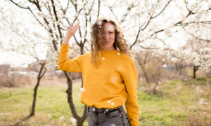 Девушка в желтом свитере на фоне цветущих веток