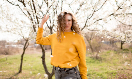Девушка в желтом свитере на фоне цветущих веток